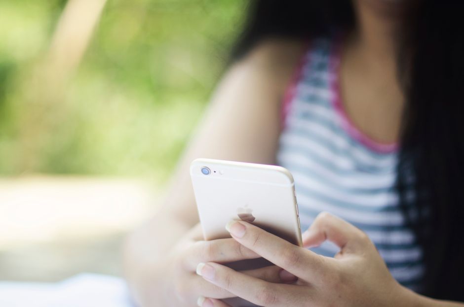Uma mulher usando um smartphone ao ar livre em um ambiente relaxante.
