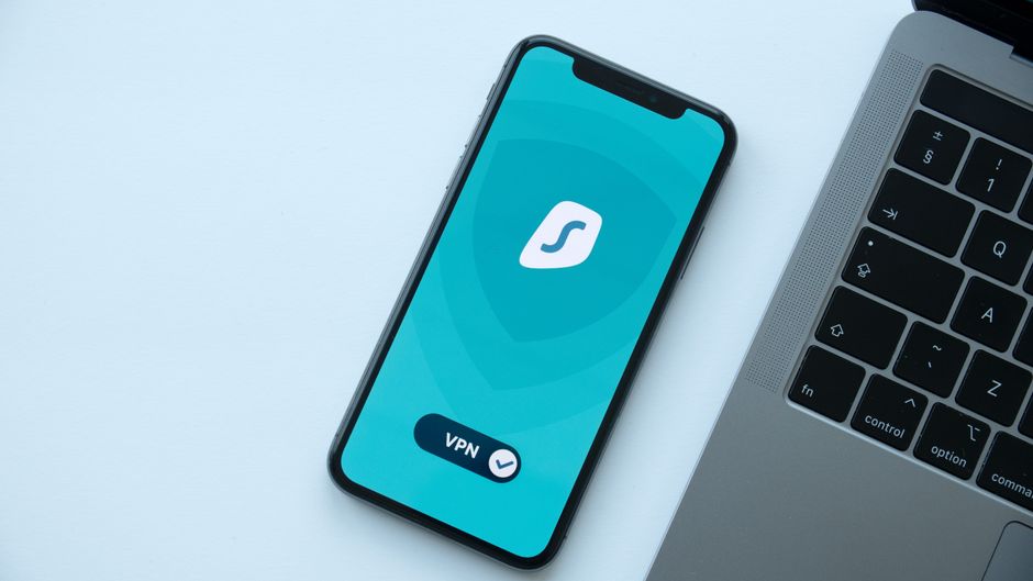 Visão superior de um smartphone mostrando um aplicativo de VPN ao lado de um laptop em uma mesa.