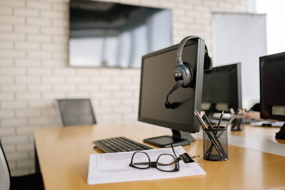 Um conjunto de mesa de escritório moderno e limpo com um computador, fones de ouvido, documentos e óculos.