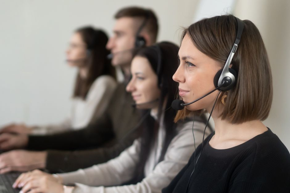 Equipe de suporte ao cliente trabalhando com headsets em um ambiente de escritório moderno.